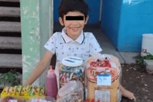 Niño vende dulces para pagar sus útiles escolares